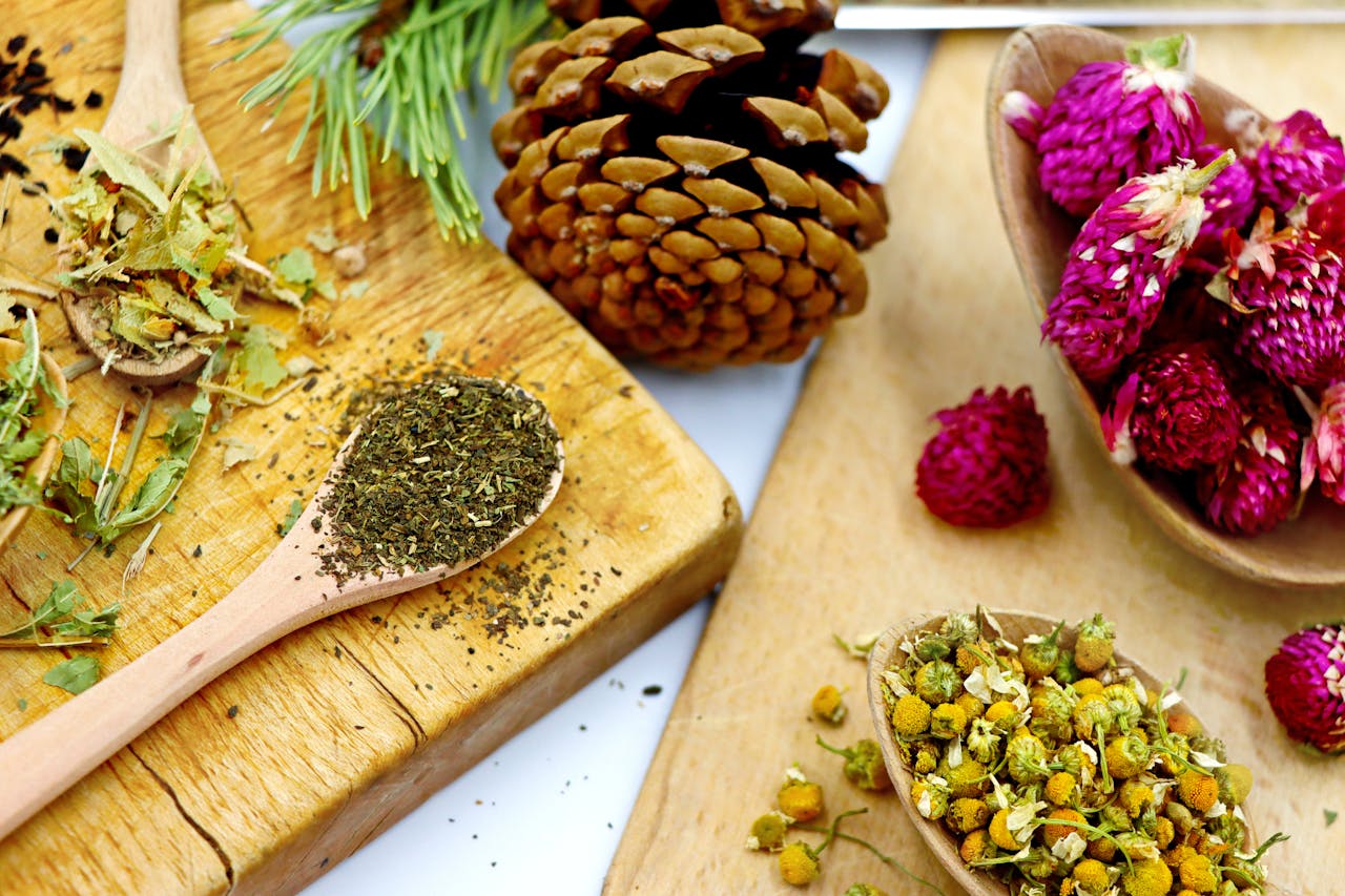 who-we-are A vibrant assortment of dry herbs and flowers for artisan tea making on rustic wooden boards.