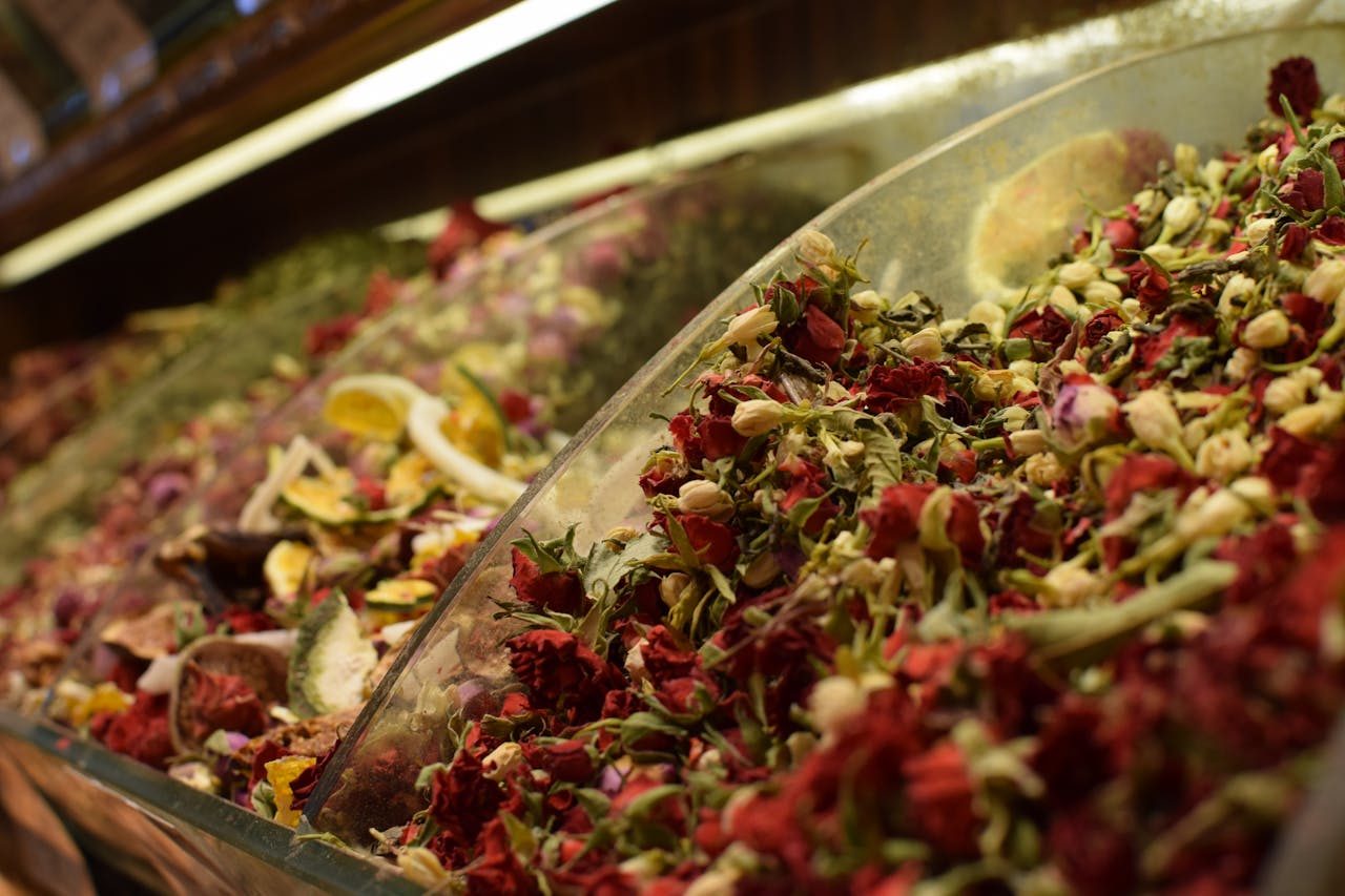Vibrant dried flowers and herbs in containers at a market, showcasing natural ingredients.